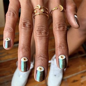 Una forma original y llamativa de llevar unas uñas con ojos es combinar un esmalte glitter con un diseño que tape las cutículas.  