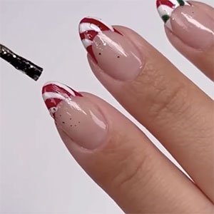 Las manicuras francesas de colores pueden ser navideñas y estar a la moda. Para recrear esta de la imagen necesitas dos capas del endurecedor de uñas Hard to resist para el fondo y los tonos Forever Yummy, Blanc y Go Overboard para los bordes.