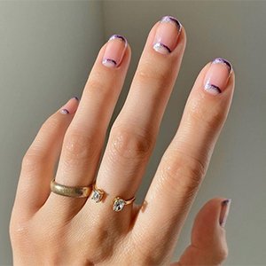 La manicura francesa con purpurina doble y media luna nos ha dejado en shock (para bien). Cálcala con la ayuda de los tonos Sexy Divide y Gadget Free de essie.