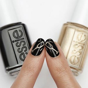 Combina un esmalte negro con otro dorado de essie y márcate una manicura navideña con nail art digna de un brindis.