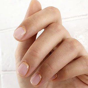 Las uñas doradas también pueden presentarse en forma de manicura invertida. Ayúdate de los esmaltes Mani Thanks o Penny Talk de essie para bordarla.