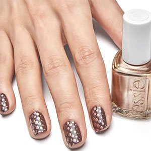 Las uñas en tonos marrones también pueden ir decoradas. ¿Qué tal con unos puntos dorados de la mano del esmalte Penny Talk de essie?