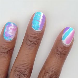 Un supertruco para que tu manicura tie-dye te salga bien es, con la segunda capa de base todavía mojada, empezar a trazar las líneas de color. En este caso, con los esmaltes Lovie Dovie, Bikini so teeny y Lilacism de essie. 