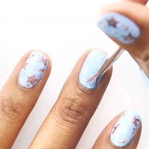 Moja un pincel en un esmalte metalizado de essie y ve creando tu diseño de uñas con estrellas. 
