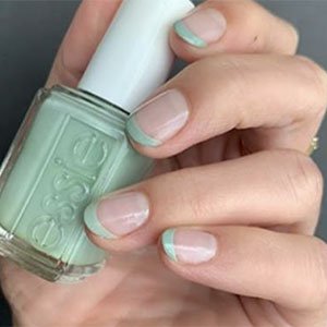 El segundo paso de estas uñas con flores que te traemos consiste en realizar una manicura francesa muy original. ¿Qué tal si el perfilado del borde de tus uñas lo haces con el verde Mint candy apple de essie?