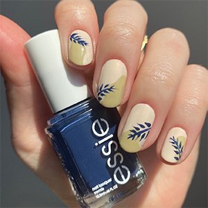 Las uñas azul oscuro pueden presentarse en forma de detalles. ¿Qué te parece este motivo vegetal de la imagen creado a partir del esmalte azul oscuro Bobbing for baubles de essie?
