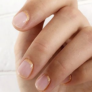 La manicura francesa invertida en clave glitter es justo el punto glam que necesitan tus uñas de primavera-verano. Consíguela con el tono Mademoiselle de essie y un toque sutil de Penny Talk enmarcado el nacimiento de la uña.